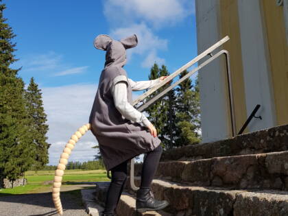 Kirkonrotta-hahmo kiipeää kirkon kiviportaita ylöspäin.