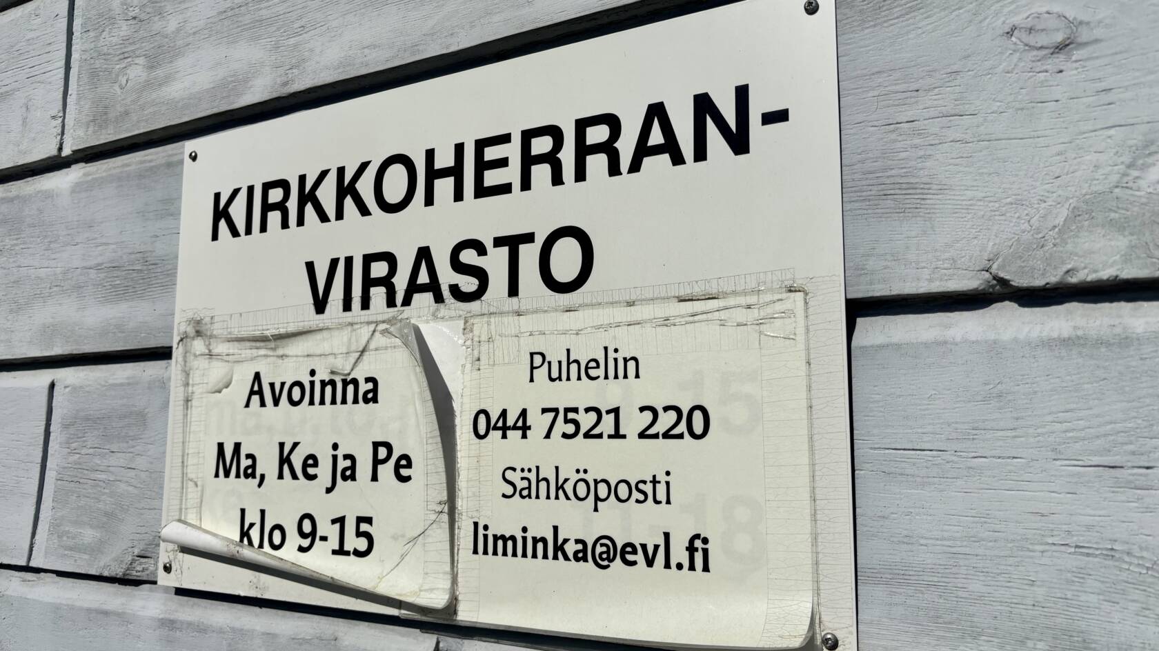 Seinässä olevassa kyltissä lukee: Kirkkoherranvirasto avoinna ma, ke ja pe klo 9-15, puhelin 044 752 1220, sähköposti liminka@evl.fi.